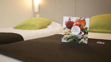 A hotel room with a neatly made bed, a green pillow, and a menu stand displaying a restaurant sign.