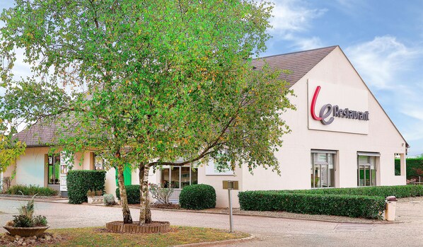A restaurant with a sign reading "Restaurant" and a large tree in front.