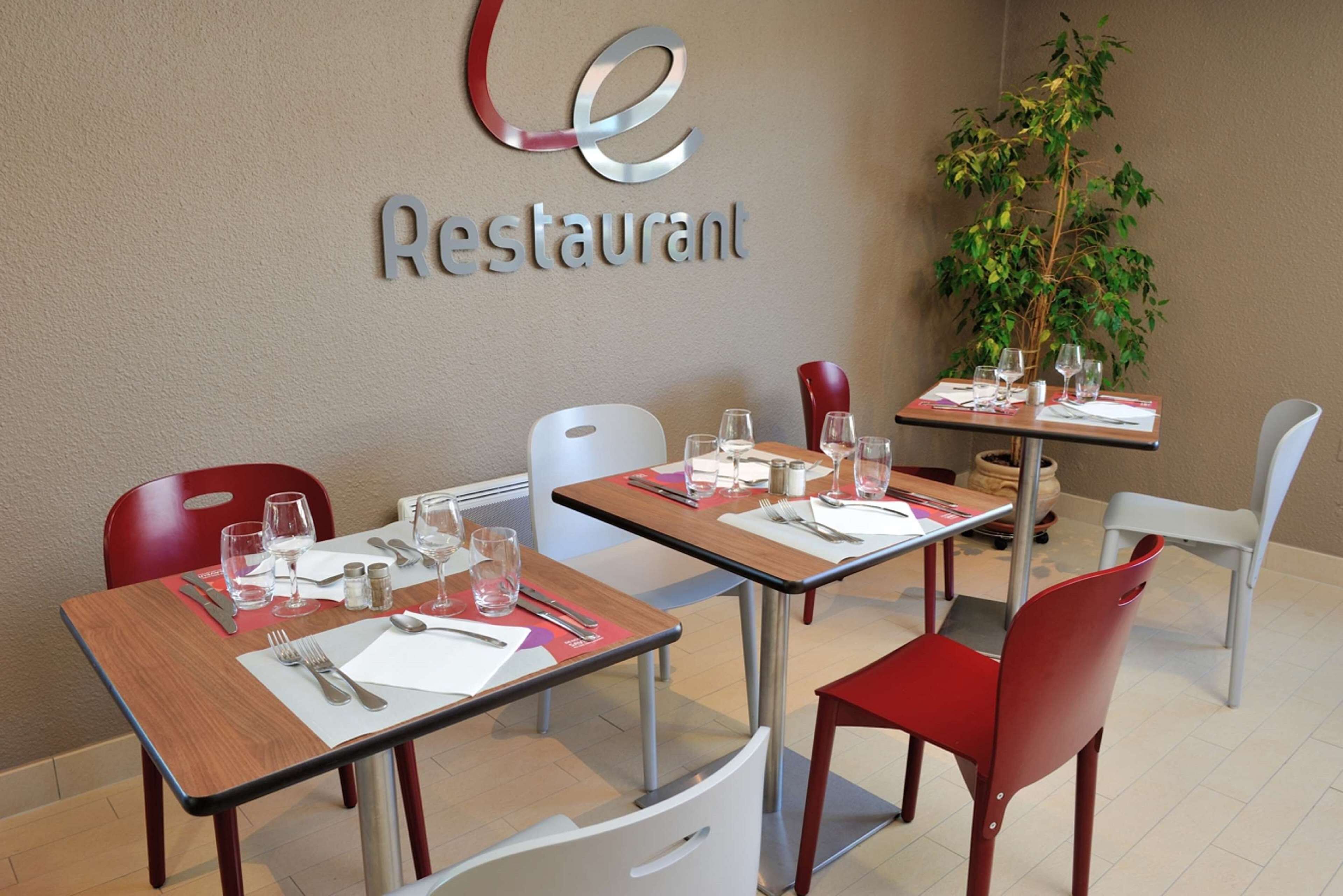 A restaurant with tables set for dining, chairs, and a potted plant.