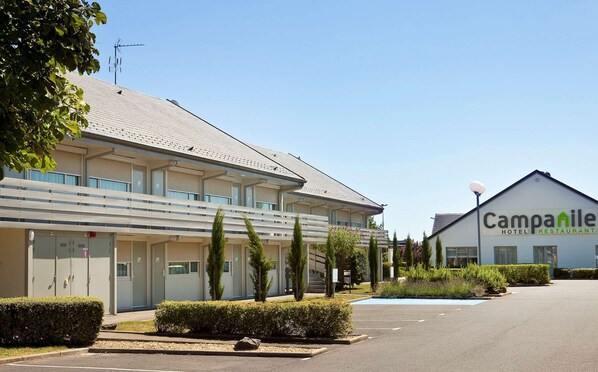 Ein Hotel mit flachem Dach, zahlreichen Fenstern und einem Parkplatz.