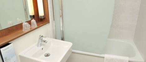 A bathroom with a white sink, a mirror, and a bathtub.