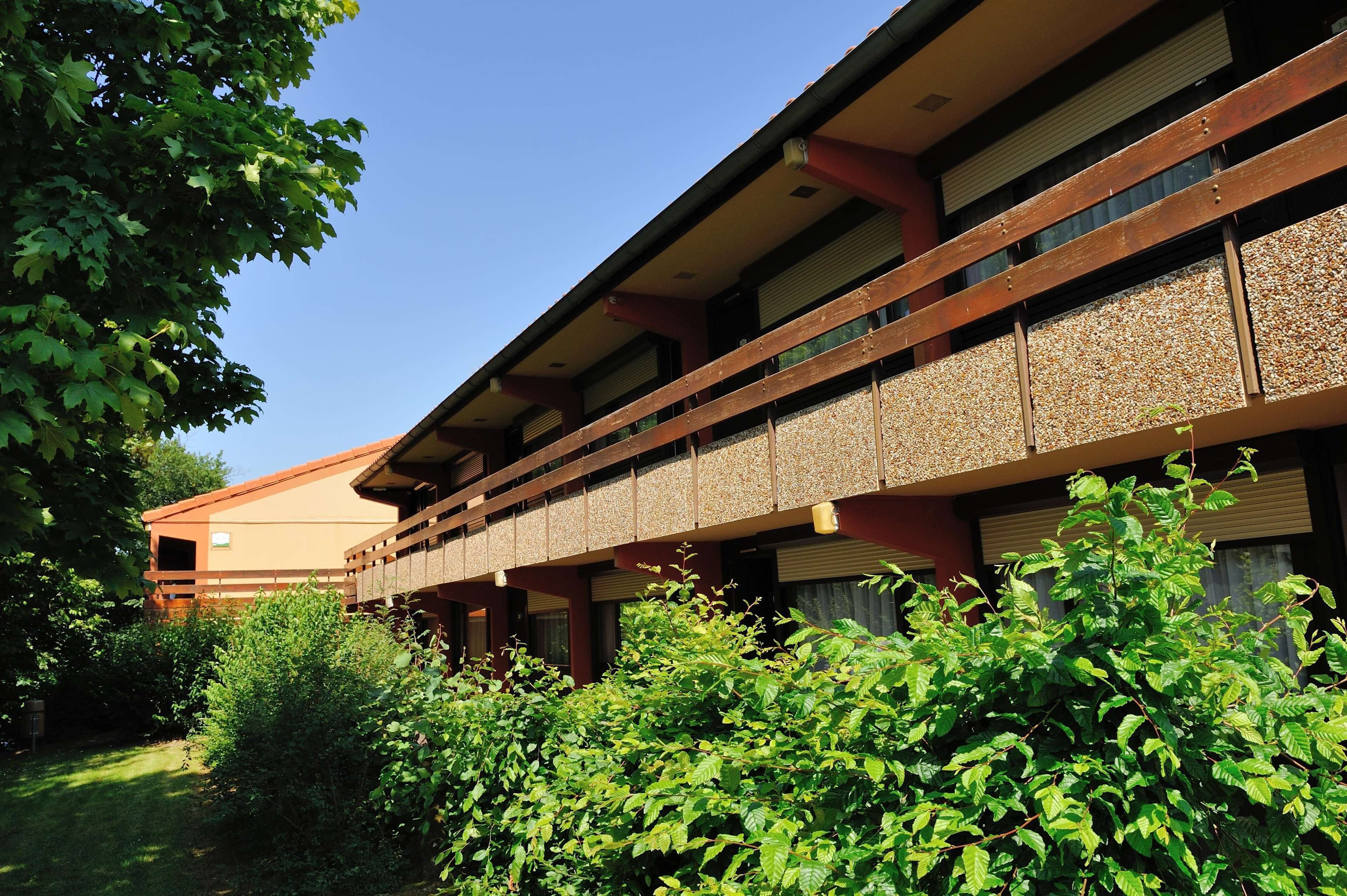 A building with a traditional architectural style, featuring a wooden balcony with a textured wall.