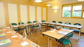 A conference room with hexagonal patterned floor tiles, green chairs, and tables labeled "Campanile."