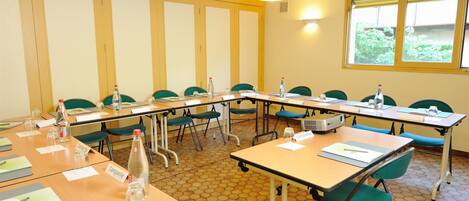 A conference room with hexagonal patterned floor tiles, green chairs, and tables labeled "Campanile."