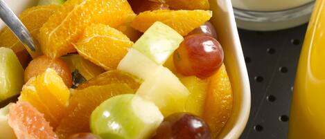 Un tazón con fruta variada, incluyendo naranjas, uvas y manzanas.