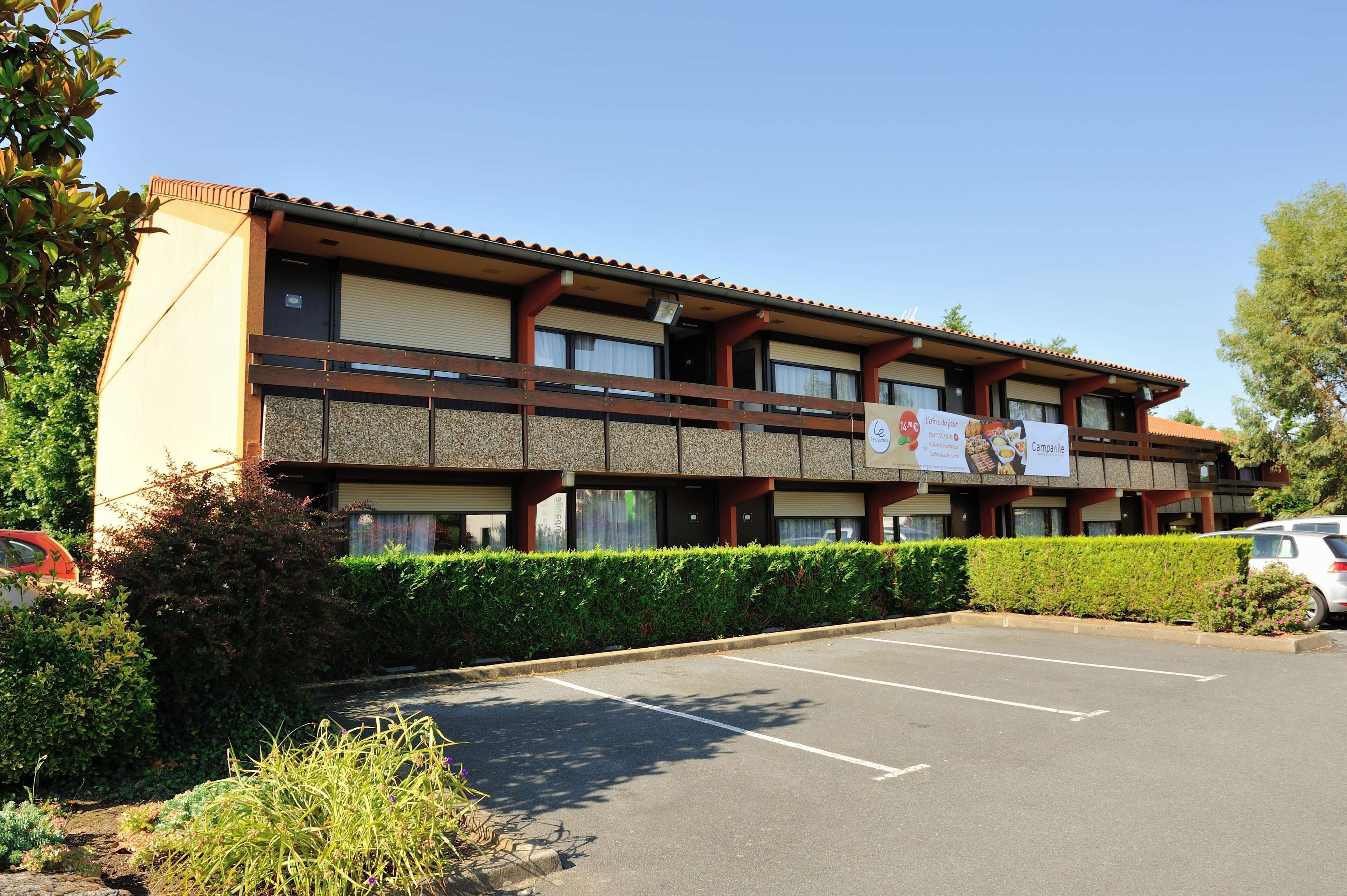A two-story hotel with a parking lot and a banner advertising a restaurant.