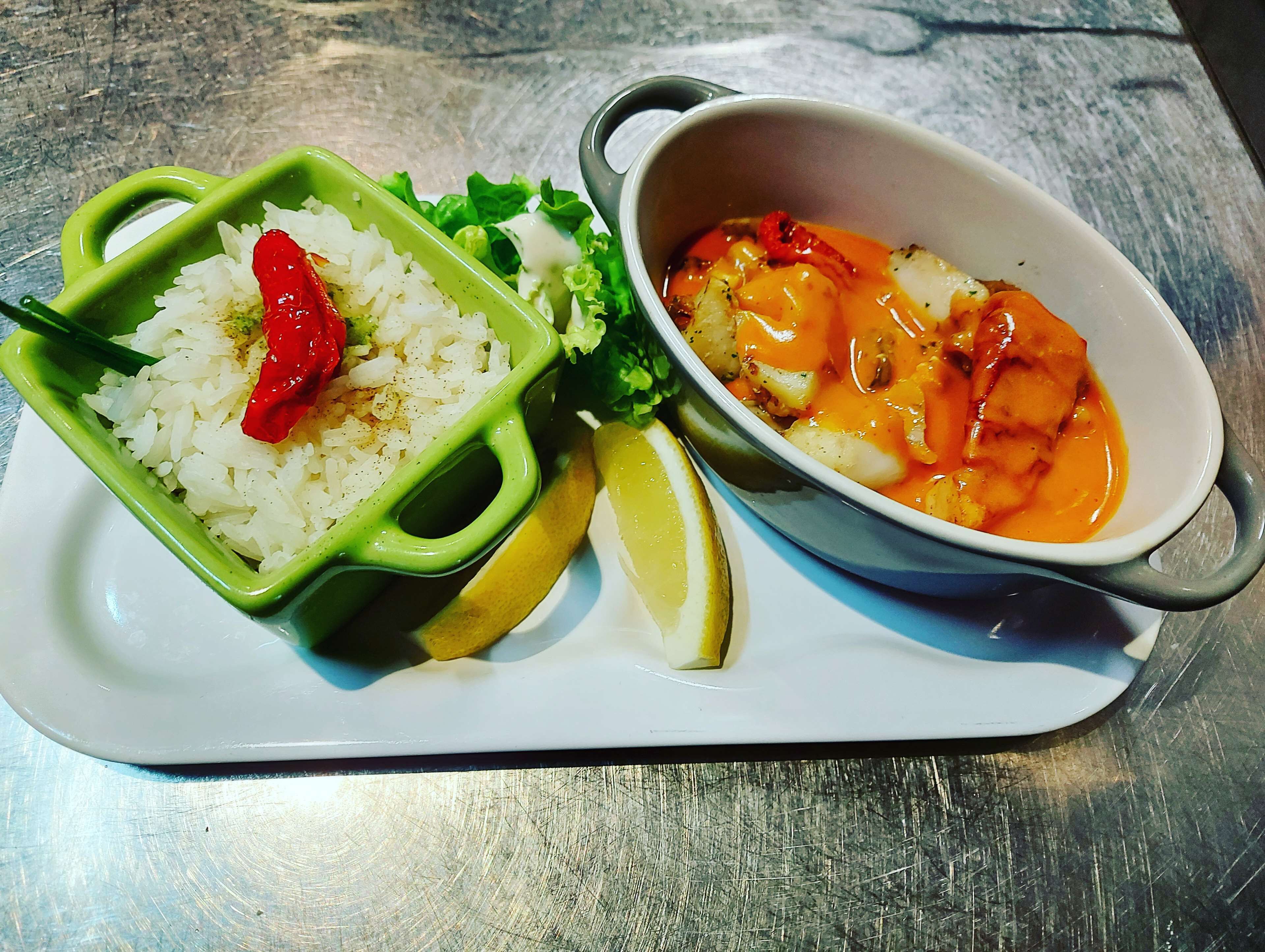 A meal consisting of rice, vegetables, and a soup with lemon slices.