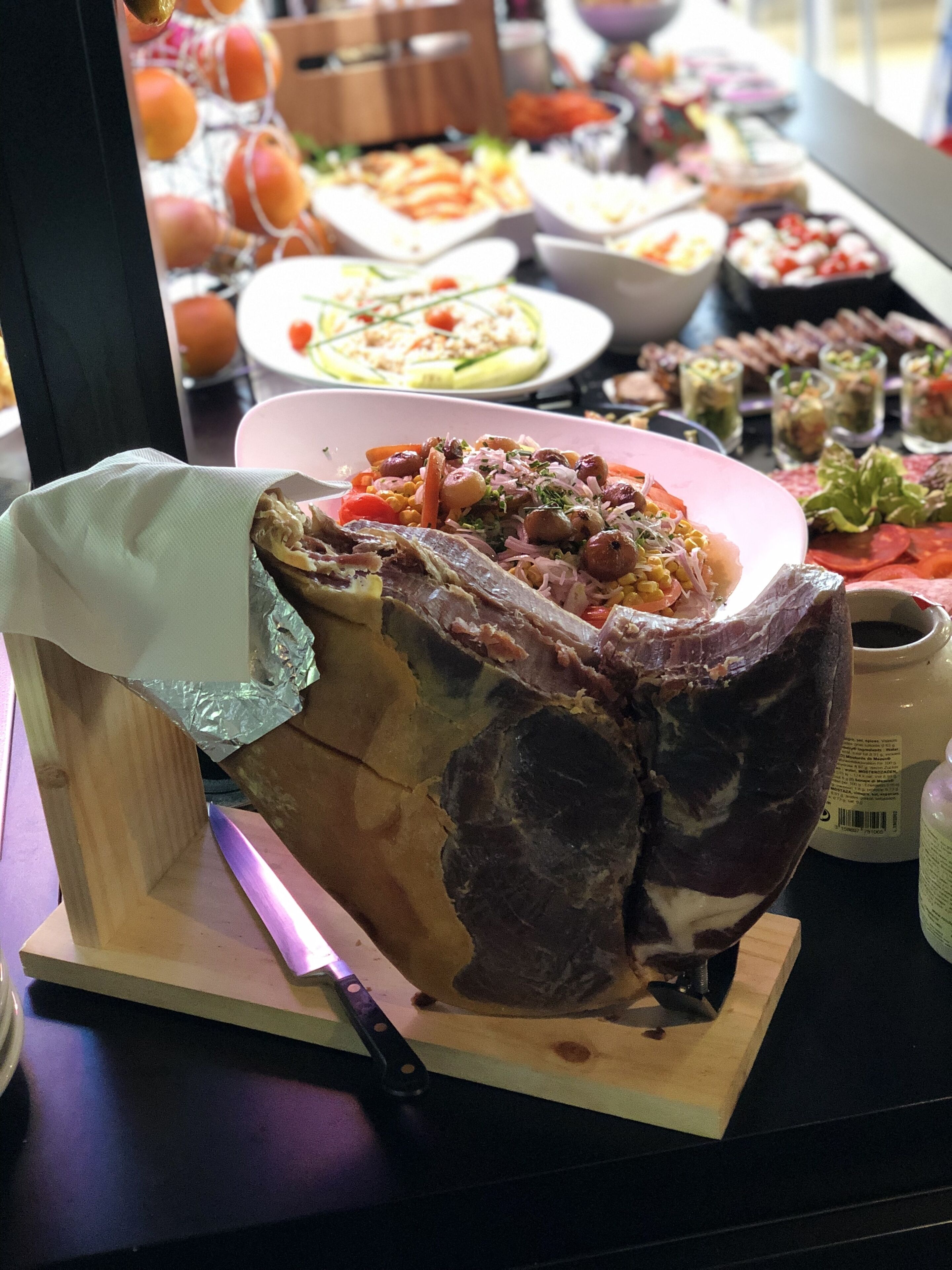 Una variedad de platos, incluyendo un gran trozo de carne asada como plato principal, rodeado de otros alimentos en una mesa.