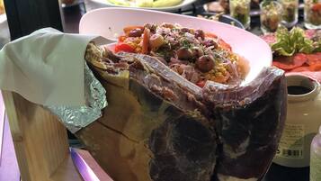Una variedad de platos, incluyendo un gran trozo de carne asada como plato principal, rodeado de otros alimentos en una mesa.