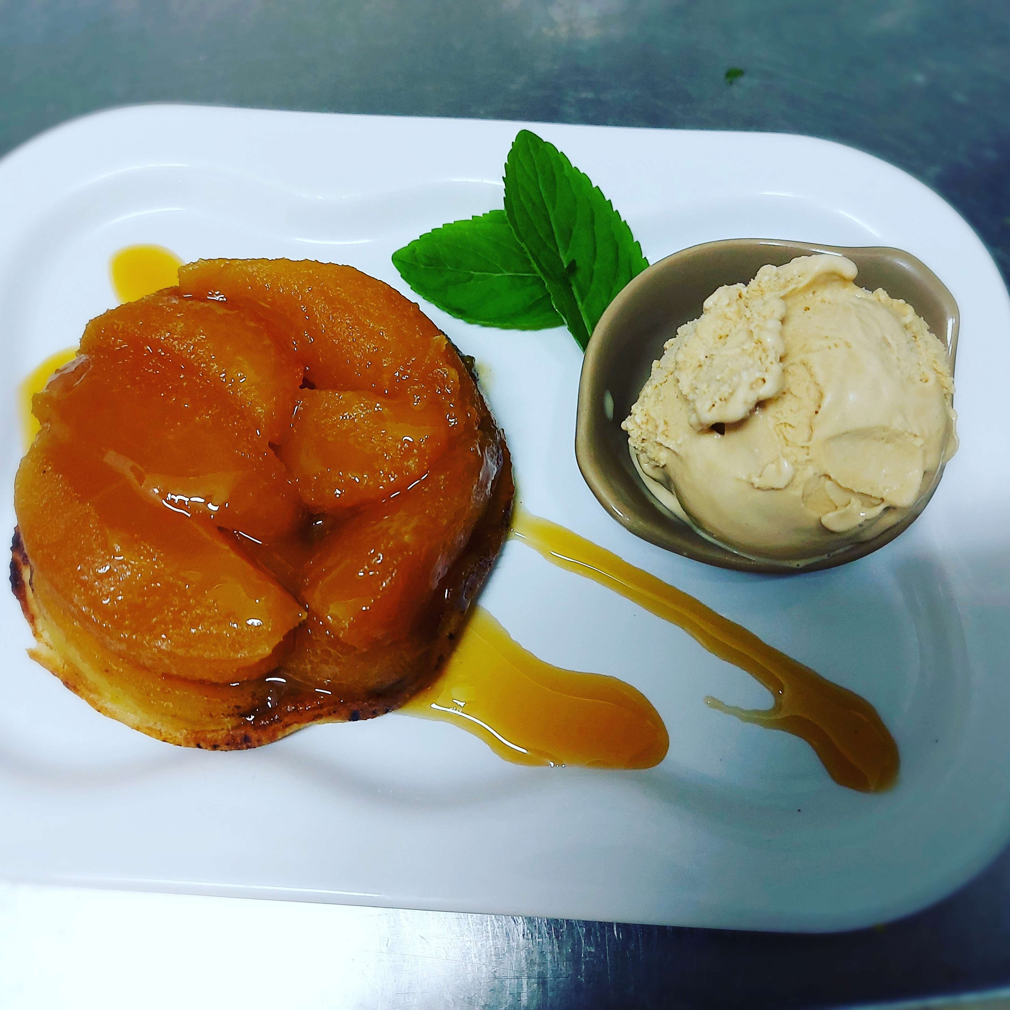 Une assiette de dessert avec une poire caramélisée et une coupe de glace à la vanille.