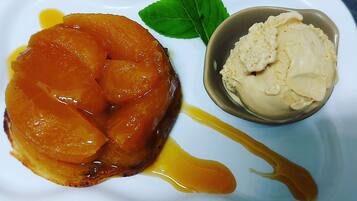 Un plato de postre con una preparación de pera caramelizada y un tazón de helado de vainilla.