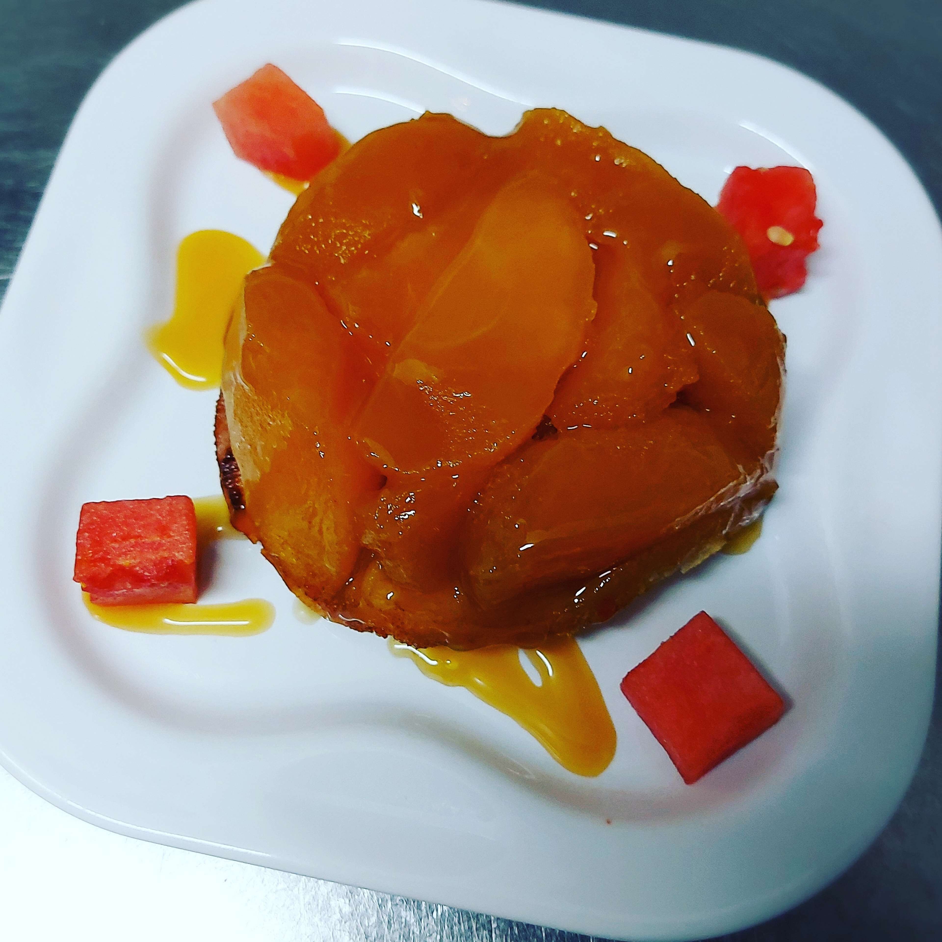 Een dessert met perziken op een wit bord.