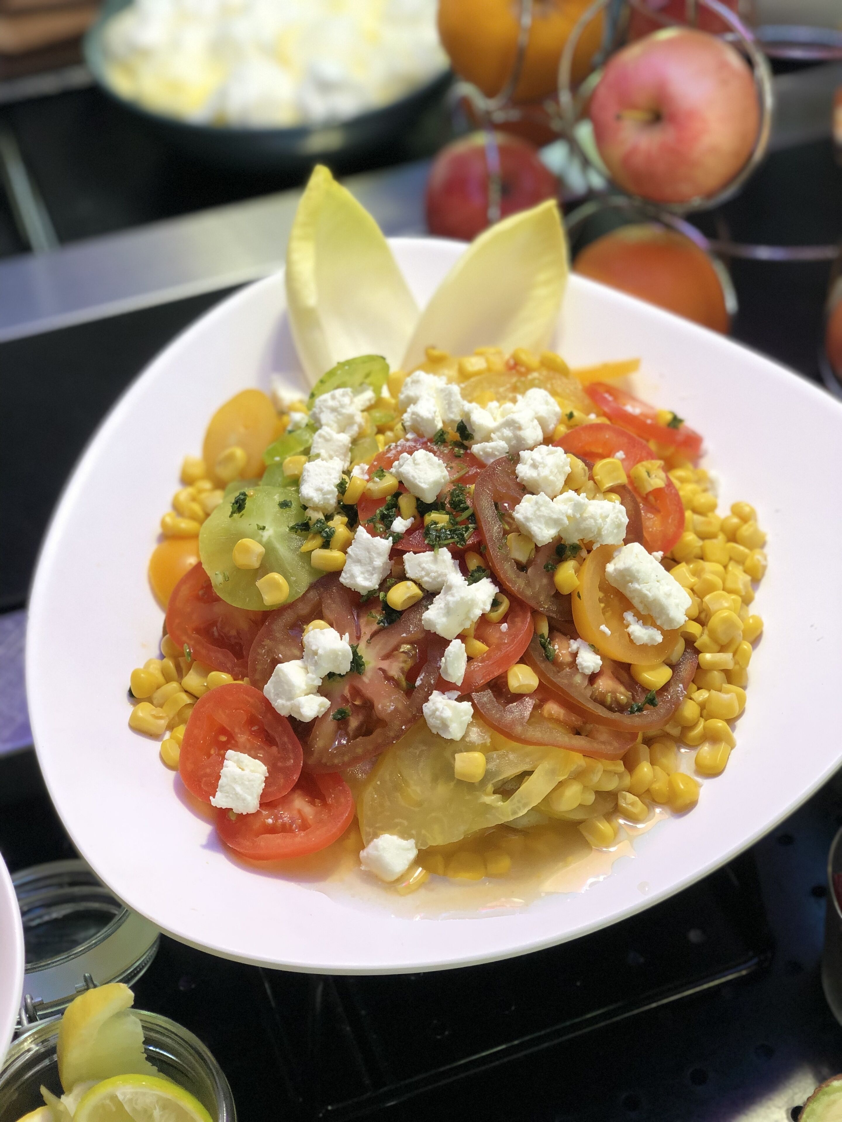 A plate of salad with tomatoes, corn, onions, and feta cheese.