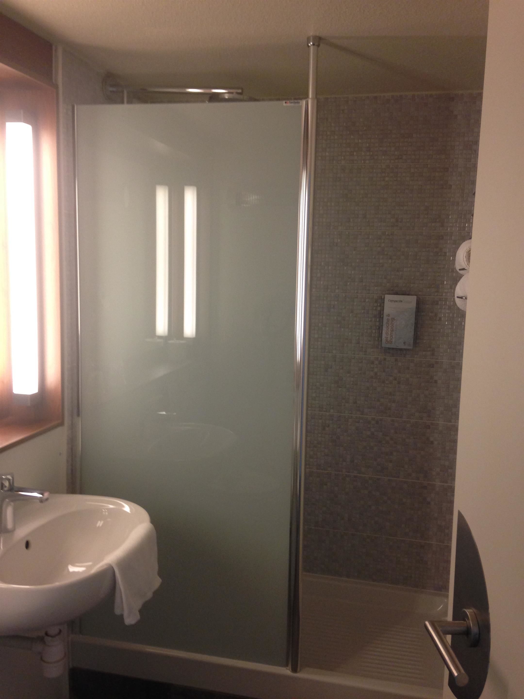 A bathroom with a glass-enclosed shower, a sink, and a towel rack.