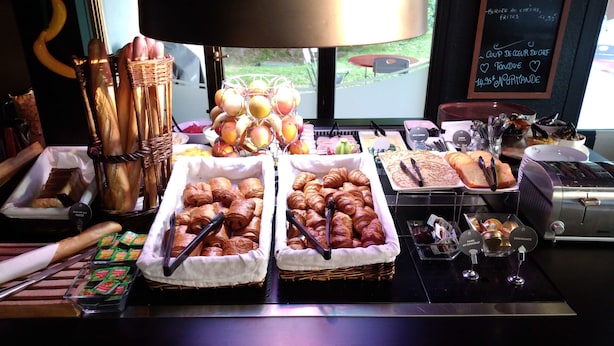 A breakfast buffet with croissants, pastries, and fruits. - Campanile Bayeux (Bayeux)