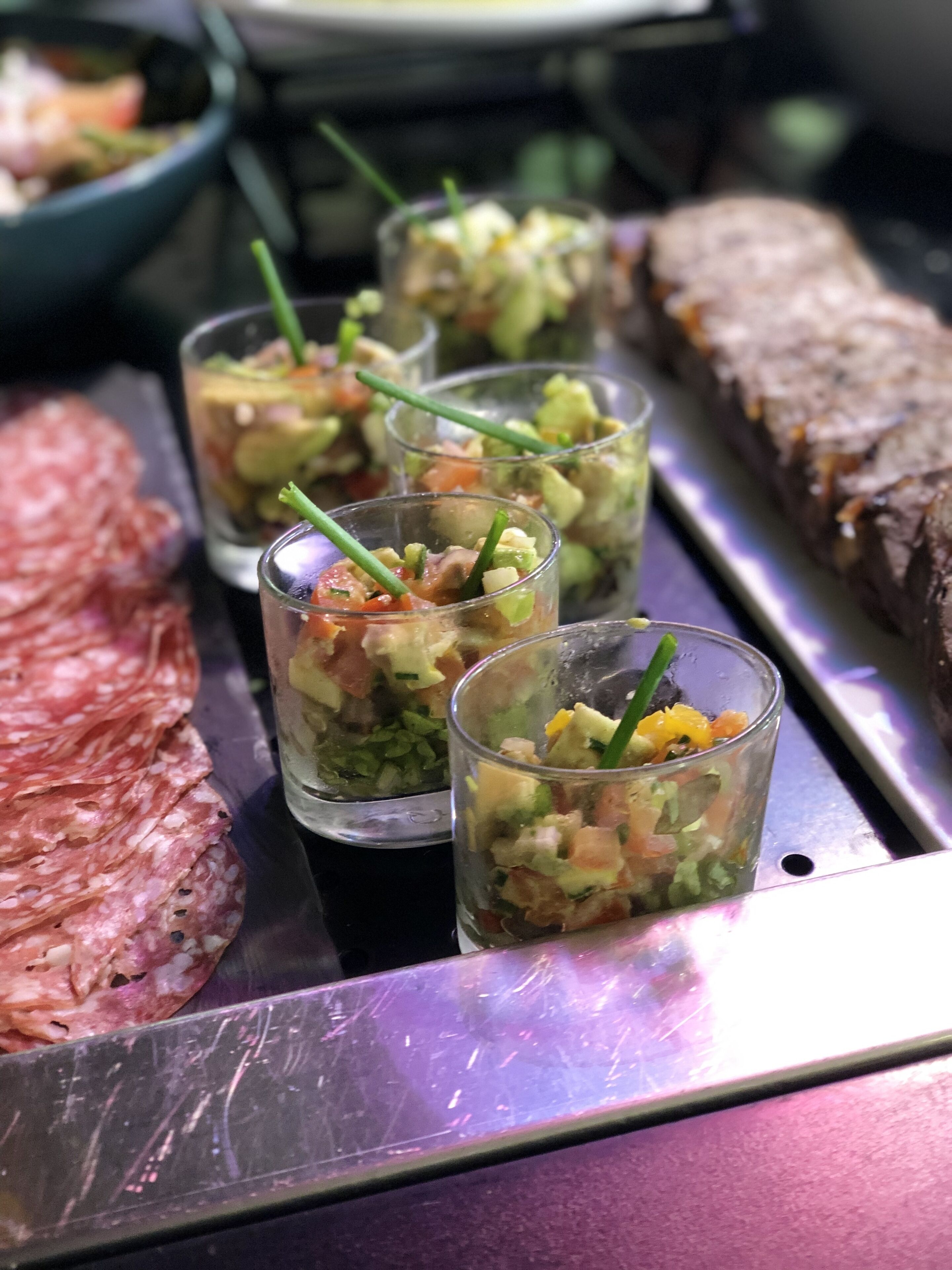 Ein Tablett mit geschnittenem Fleisch, eine Schüssel mit gewürfelten Gemüsesorten und ein Stück Brot.