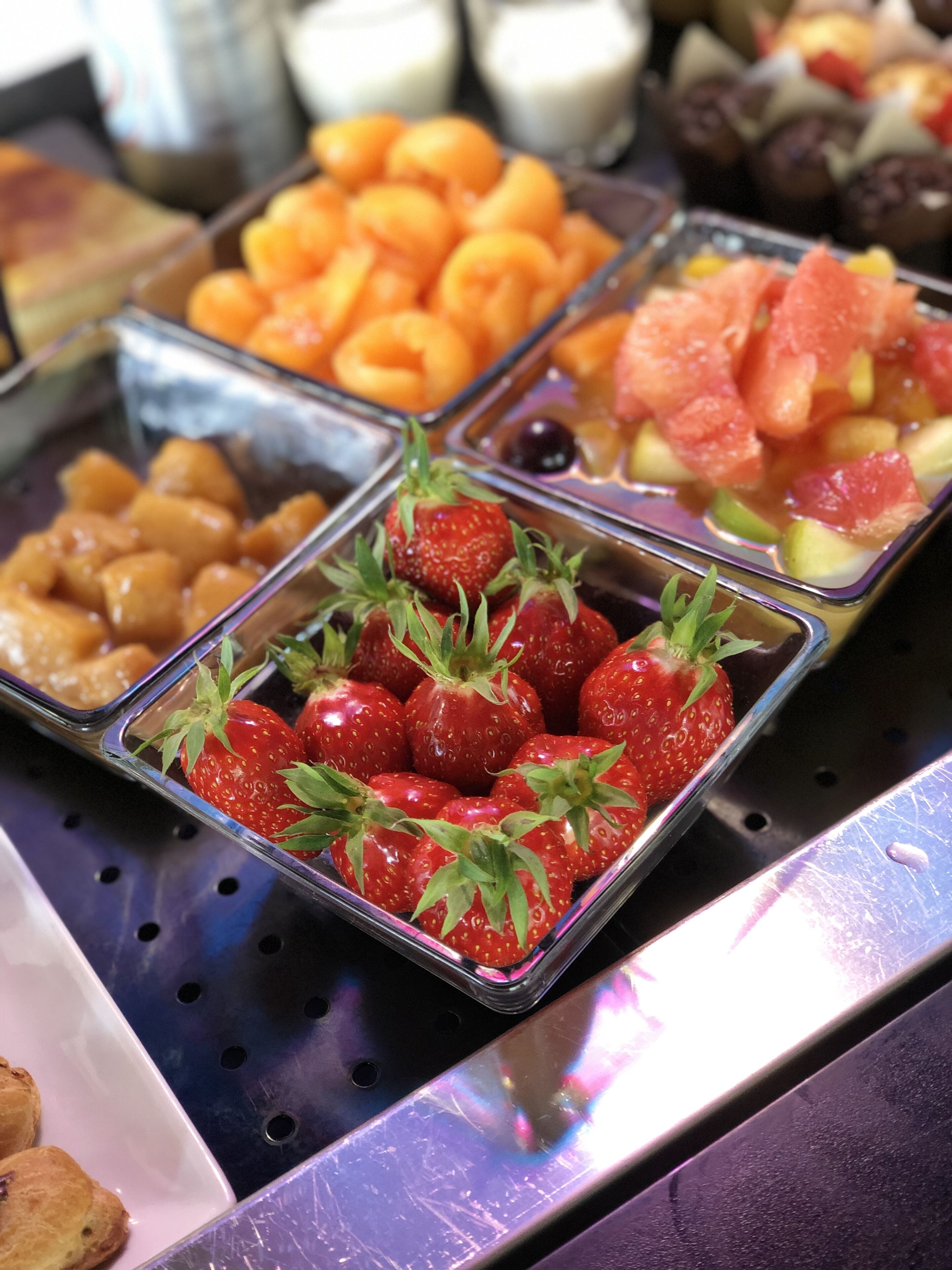 A buffet with various fruits and pastries.