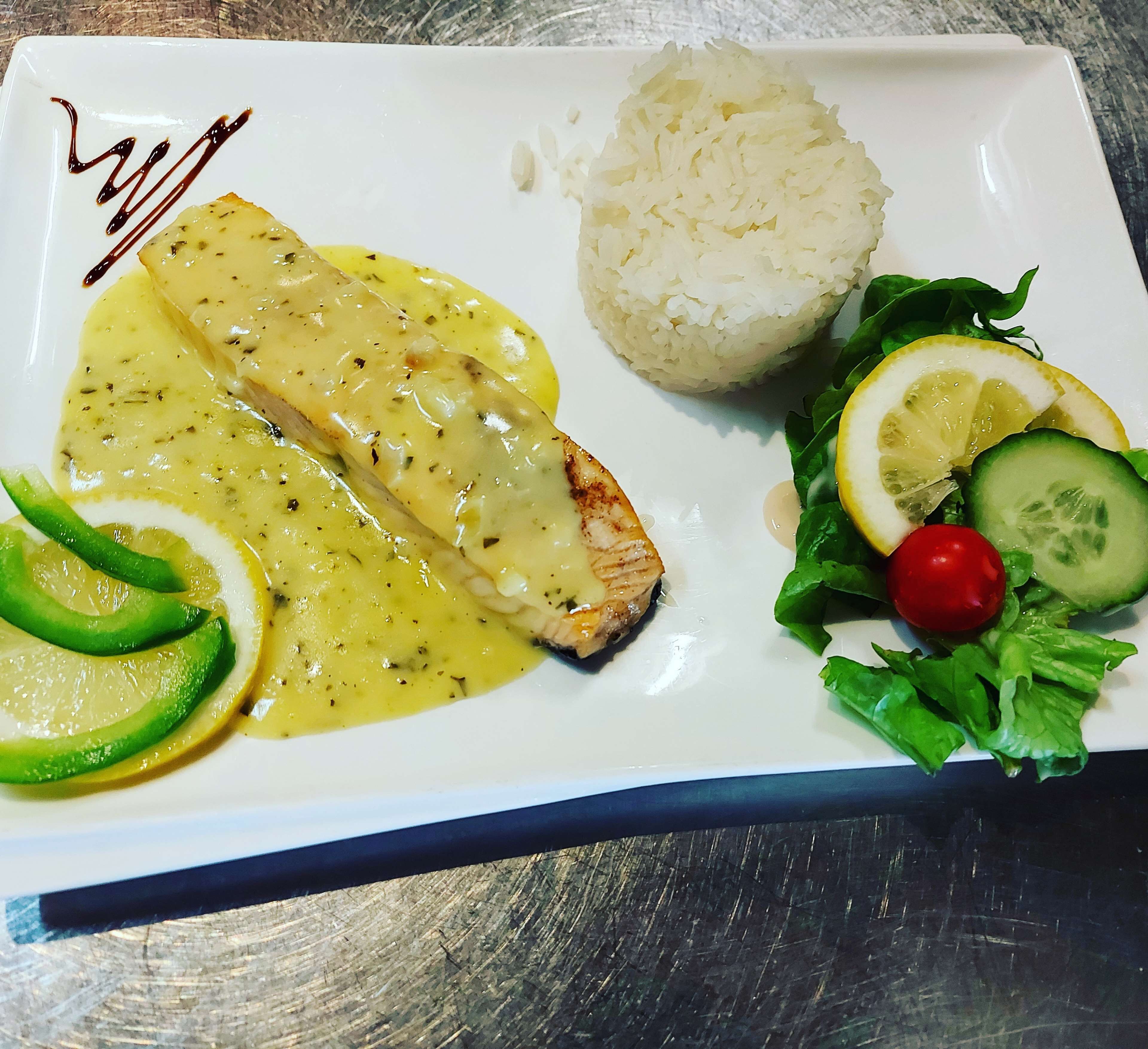 A plate with a piece of fish, rice, and a side salad.