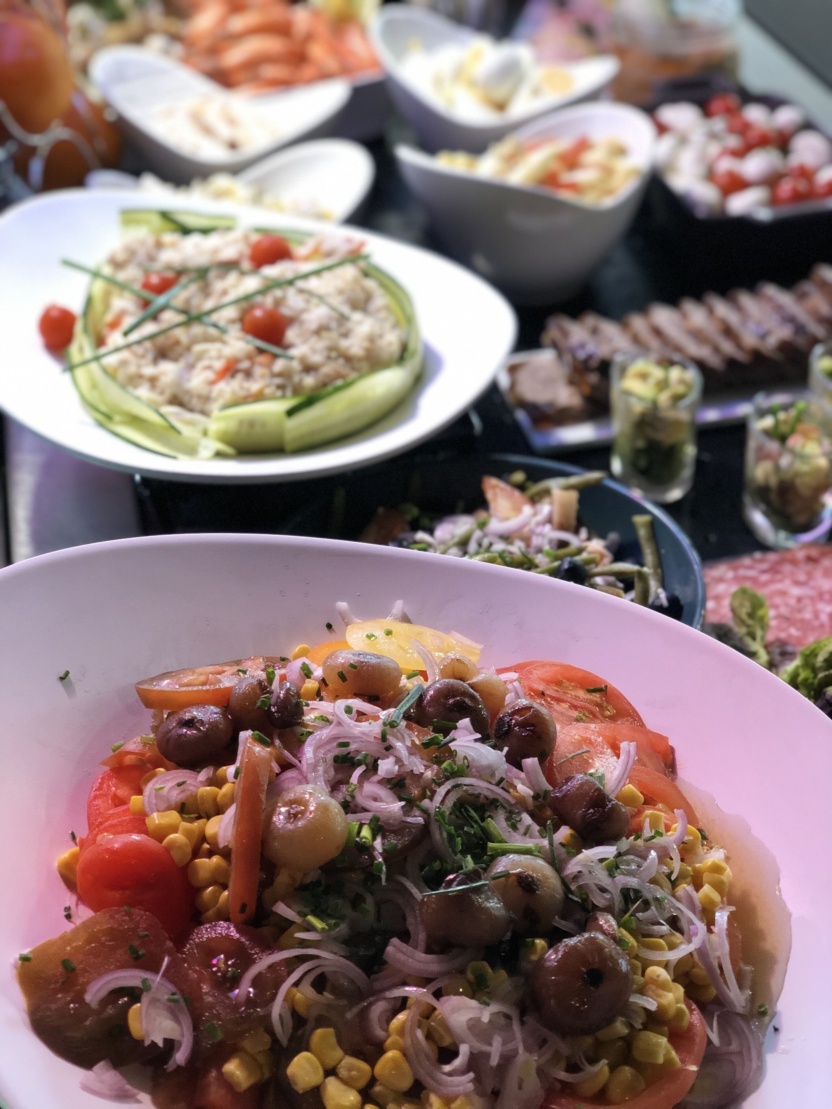 A table with various dishes including a salad with corn, tomatoes, and onions.