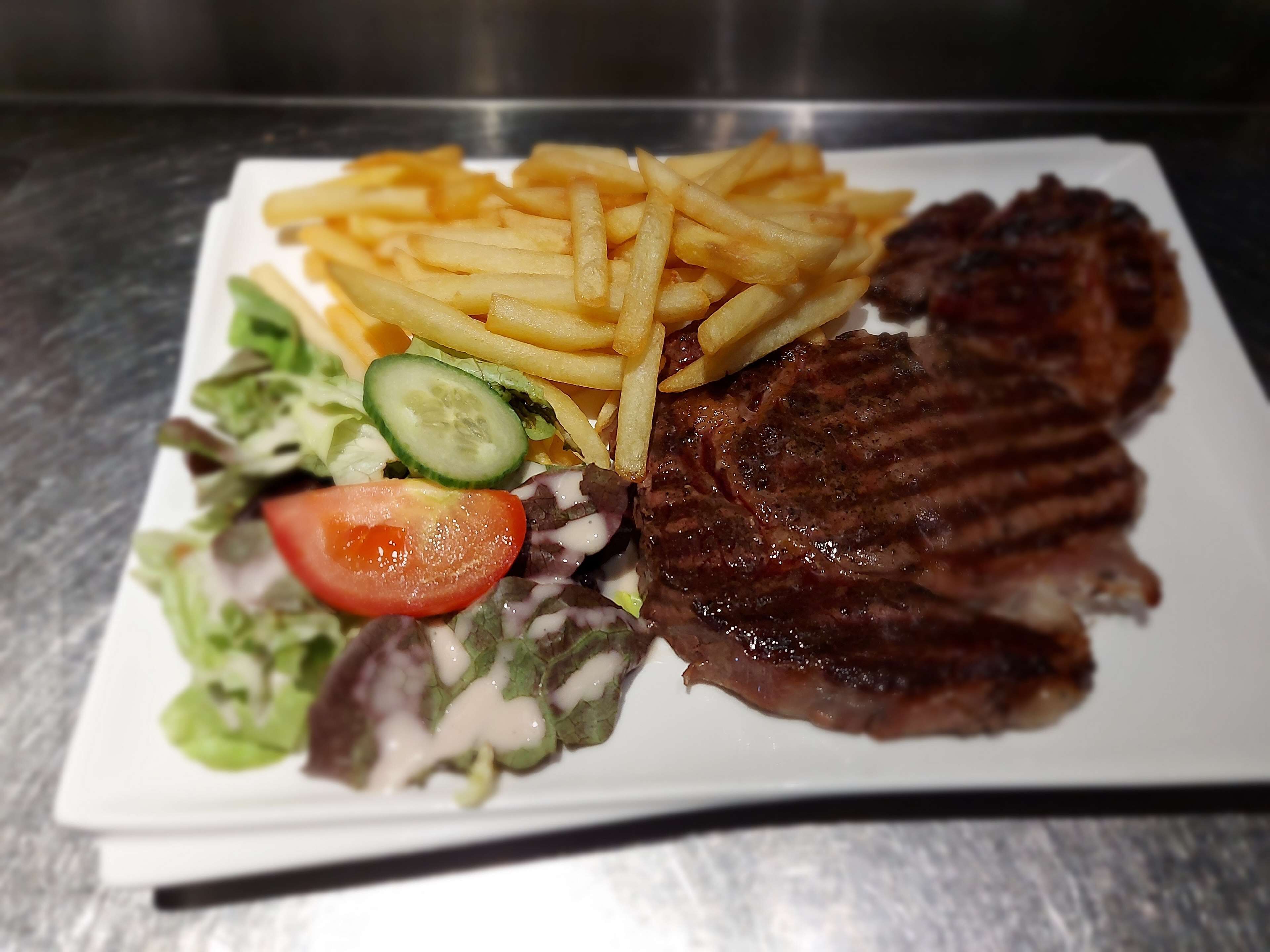 A plate with grilled steak, French fries, and a salad.