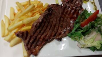 A plate with grilled steak, French fries, and a side salad.