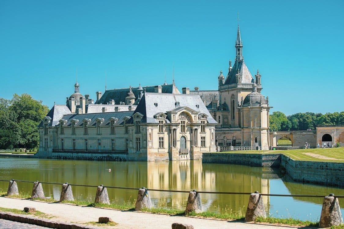 A historic building with a large courtyard and a river in the foreground.