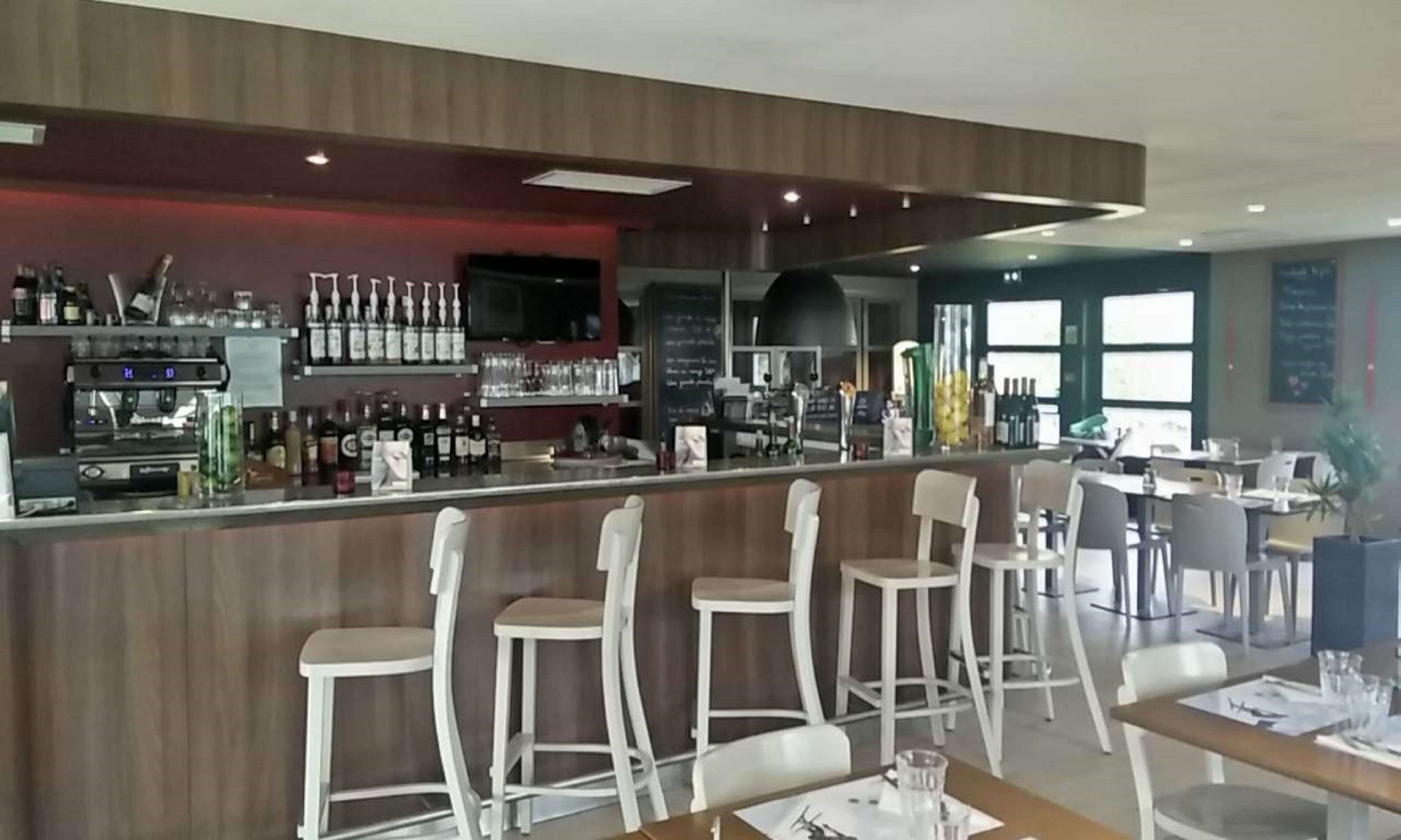 Zona de bar con taburetes y una barra, taburetes de bar y mostrador.