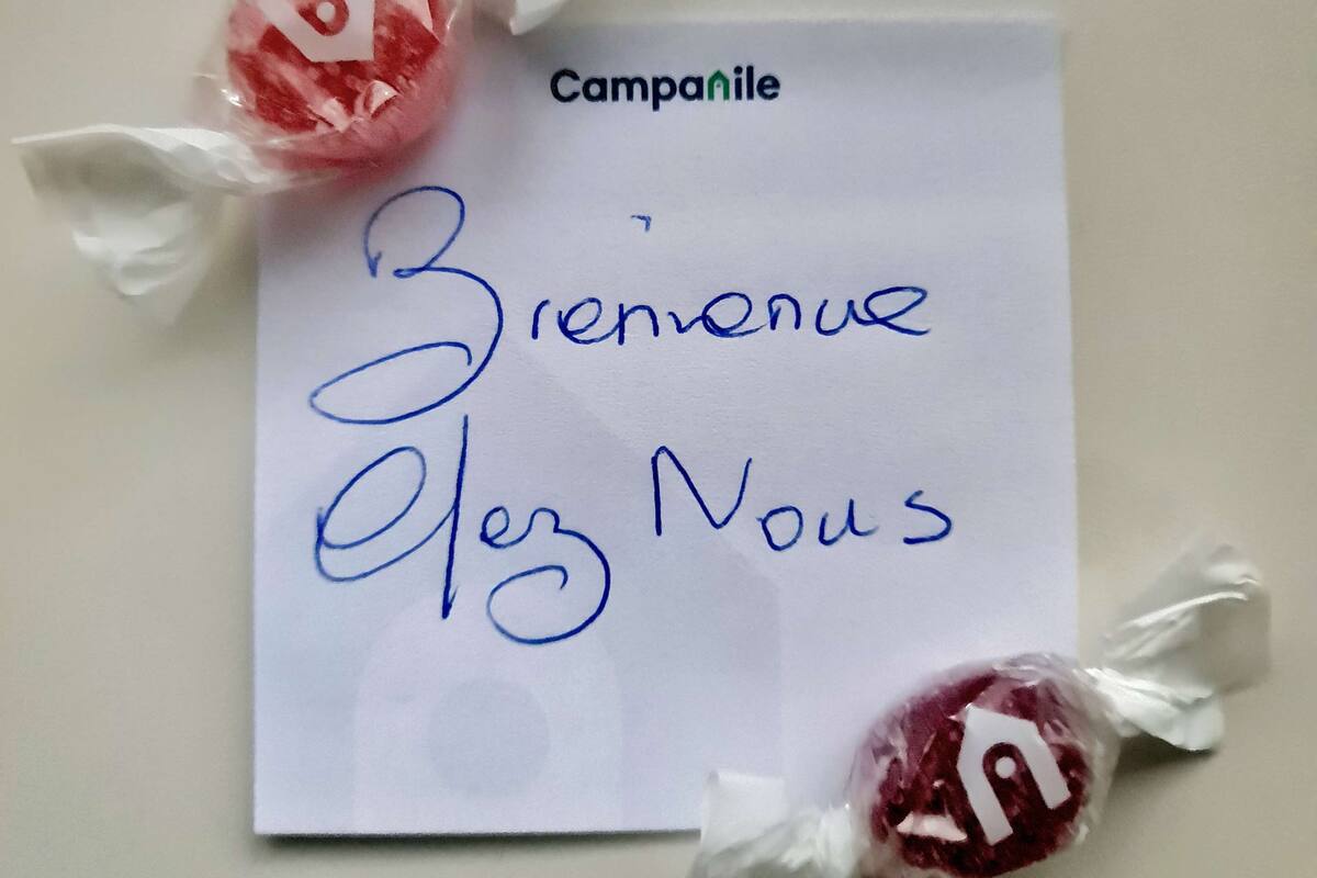 Una tarjeta con 'Campanile' y 'Bienvenue Chez Nous' escrito, rodeada por dos piruletas.