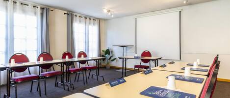 A conference room with tables, chairs, name tags, and a projector screen.