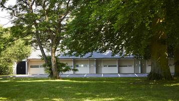 A building with a garage door, a covered parking area, and a grassy lawn.
