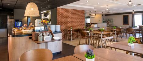 A modern cafe with a brick wall, wooden tables, and hanging pendant lights.