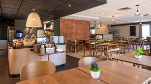 A modern cafe with a brick wall, wooden tables, and hanging pendant lights.