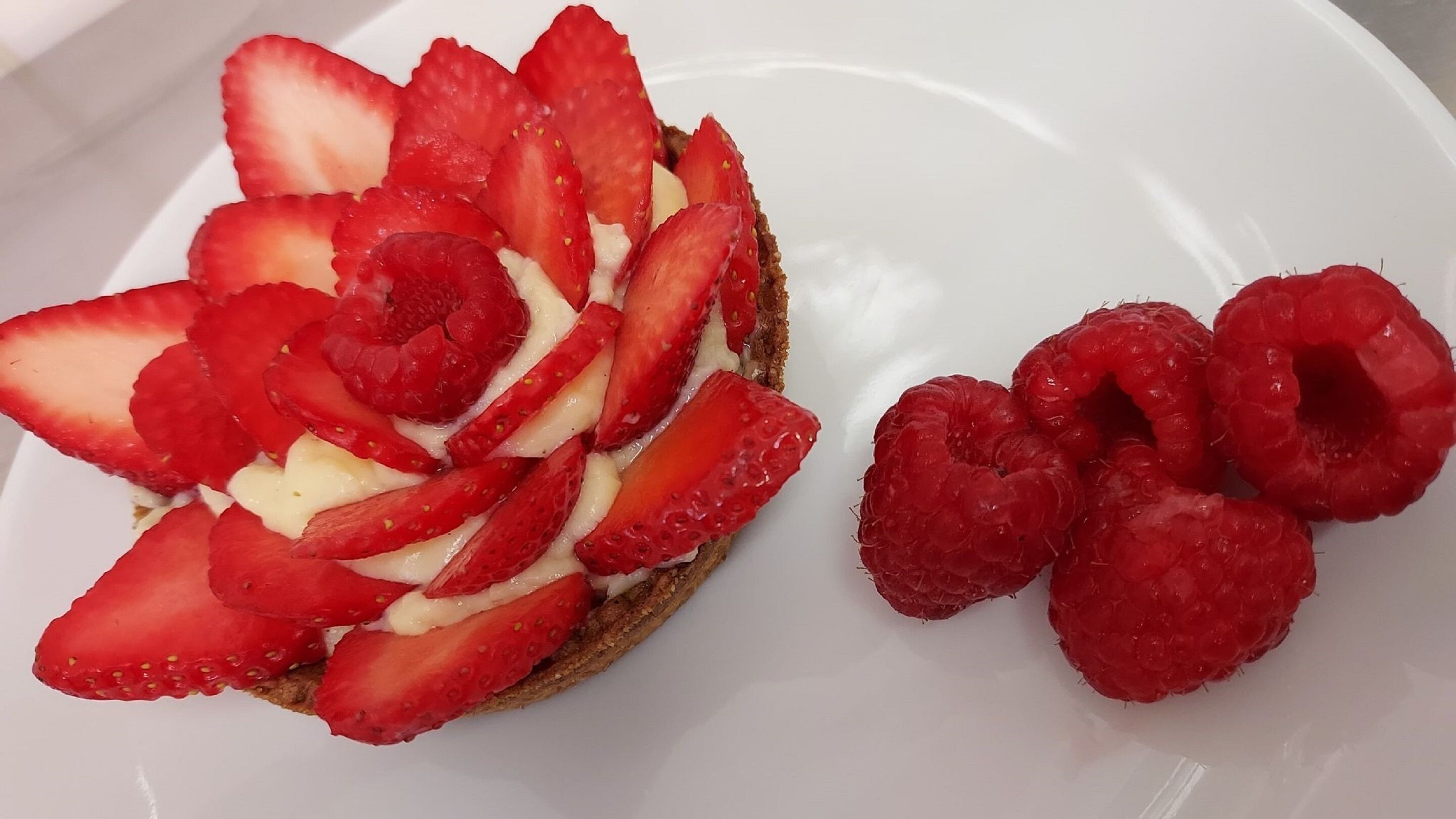 A plate with a slice of toast topped with strawberries and raspberries.