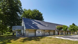 Un motel à deux étages, doté d’un toit plat, de grandes fenêtres et d’un espace de stationnement couvert.