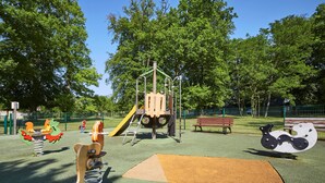 Une aire de jeux dotée de diverses installations, notamment un toboggan, des balançoires et une structure d’escalade.