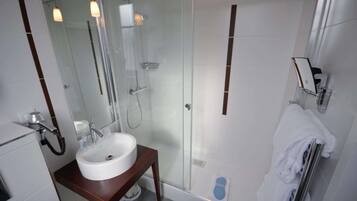 Ein modernes Badezimmer mit einer gläsernen Dusche, einem weißen Waschbecken und einem Handtuchhalter.