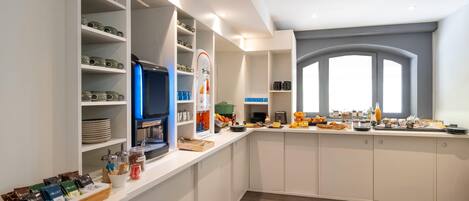Una cocina moderna con armarios blancos, horno integrado y una barra desayunadora con diversos alimentos.