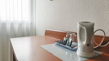 Une table avec une bouilloire électrique blanche, un plateau avec des bouteilles et un tapis.