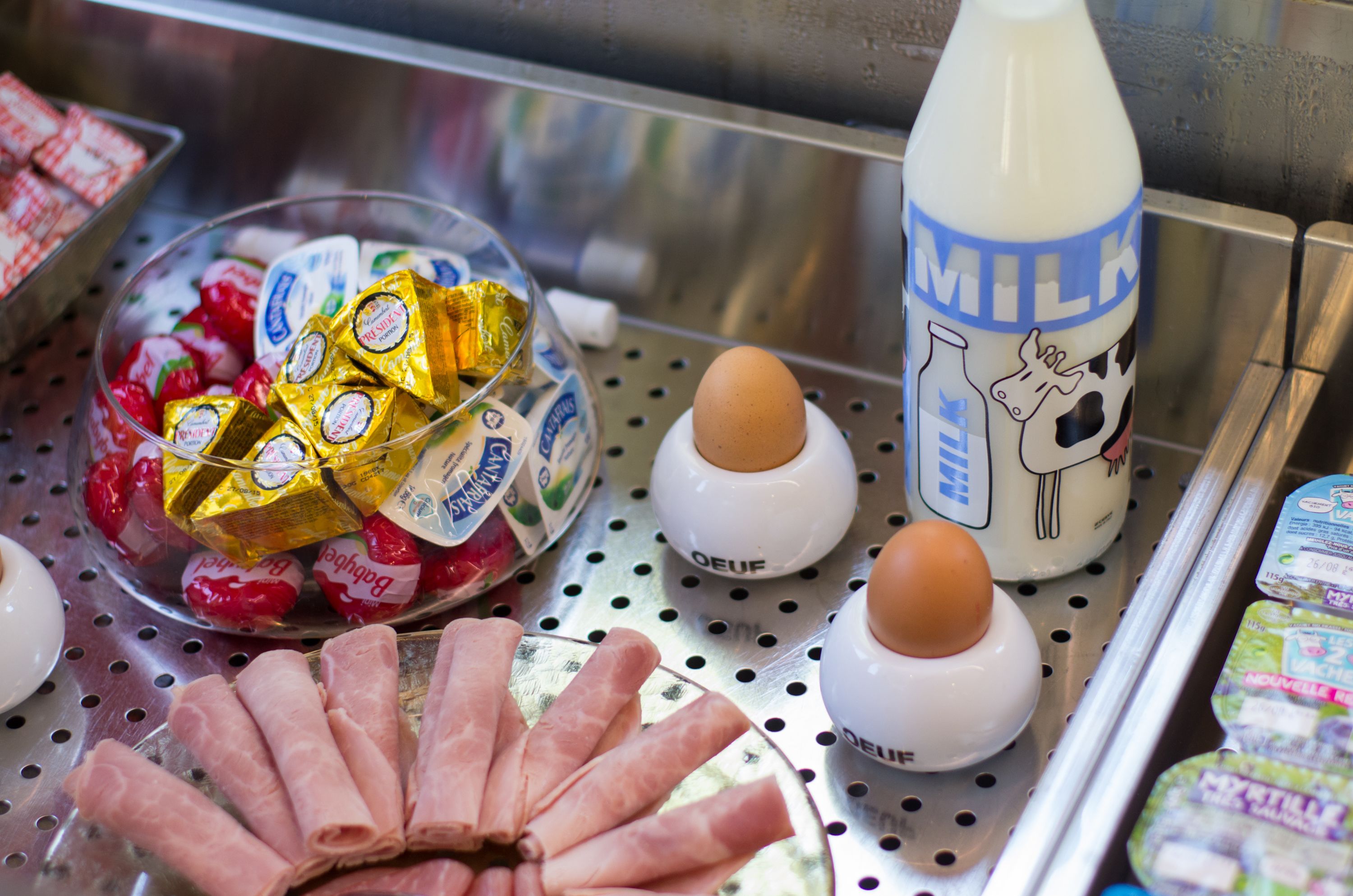 Mostrador refrigerado con diversos productos lácteos, como queso empaquetado, huevos y leche.