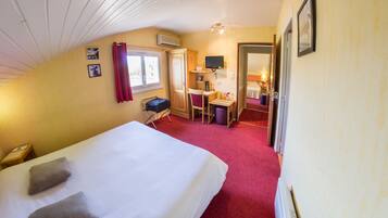Ein Hotelzimmer mit Bett, Schreibtisch, Stuhl, kleinem Tisch, Lampe und Fernseher.