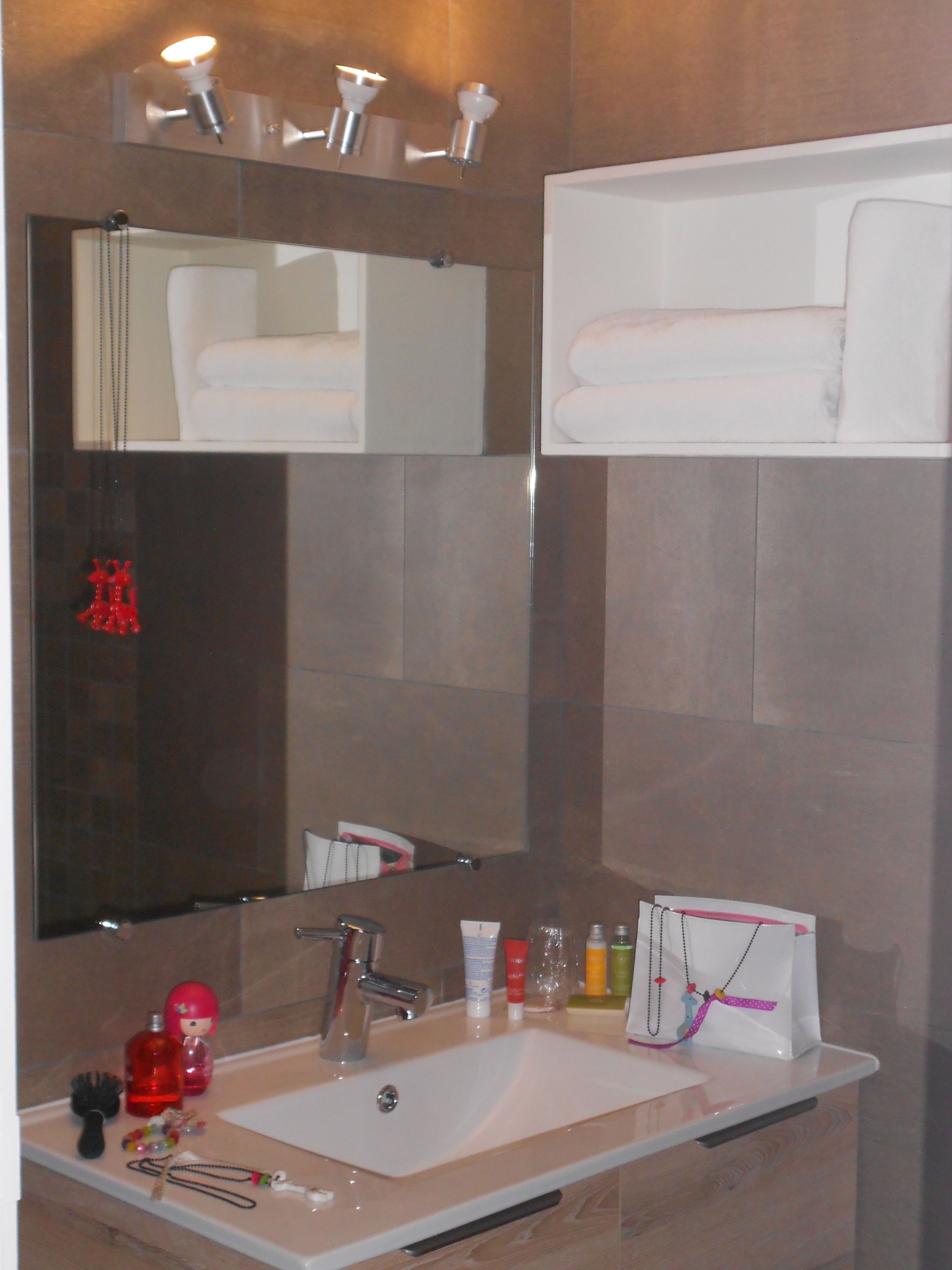 Un baño con un espejo grande, un lavabo y un perchero para toallas.