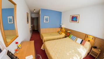 Une chambre d’hôtel avec deux lits, un bureau, une chaise, un miroir et une table de chevet avec une lampe.