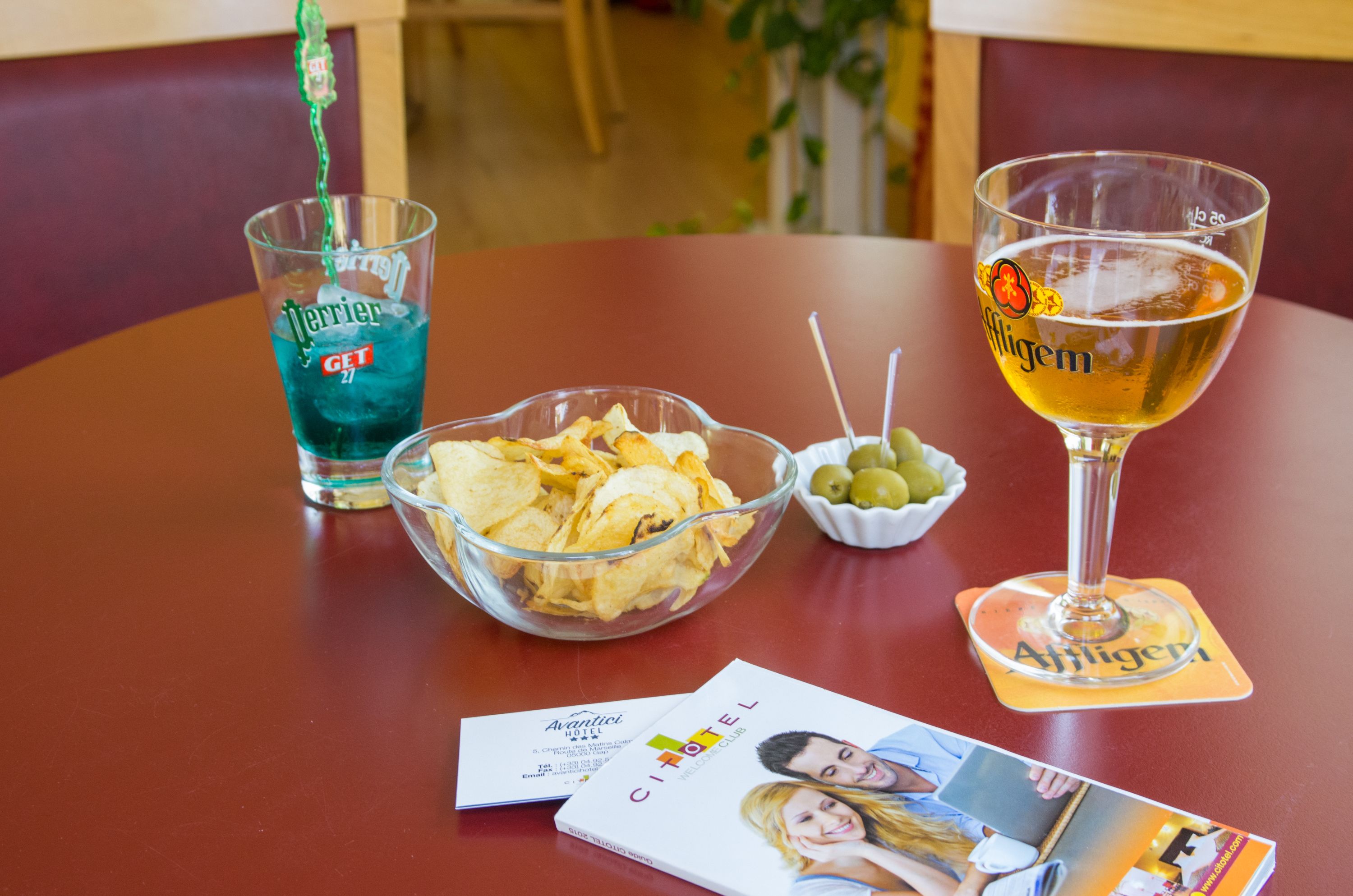 Ett bord med en skål med chips, två glas med dryck och ett par underlägg.