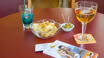 Ett bord med en skål med chips, två glas med dryck och ett par underlägg.