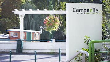 Señal para el Hotel y Restaurante Campanile, con una pérgola blanca y flores colgantes al fondo.
