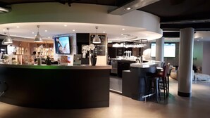 A modern bar area with a curved counter, pendant lighting, and a television screen.