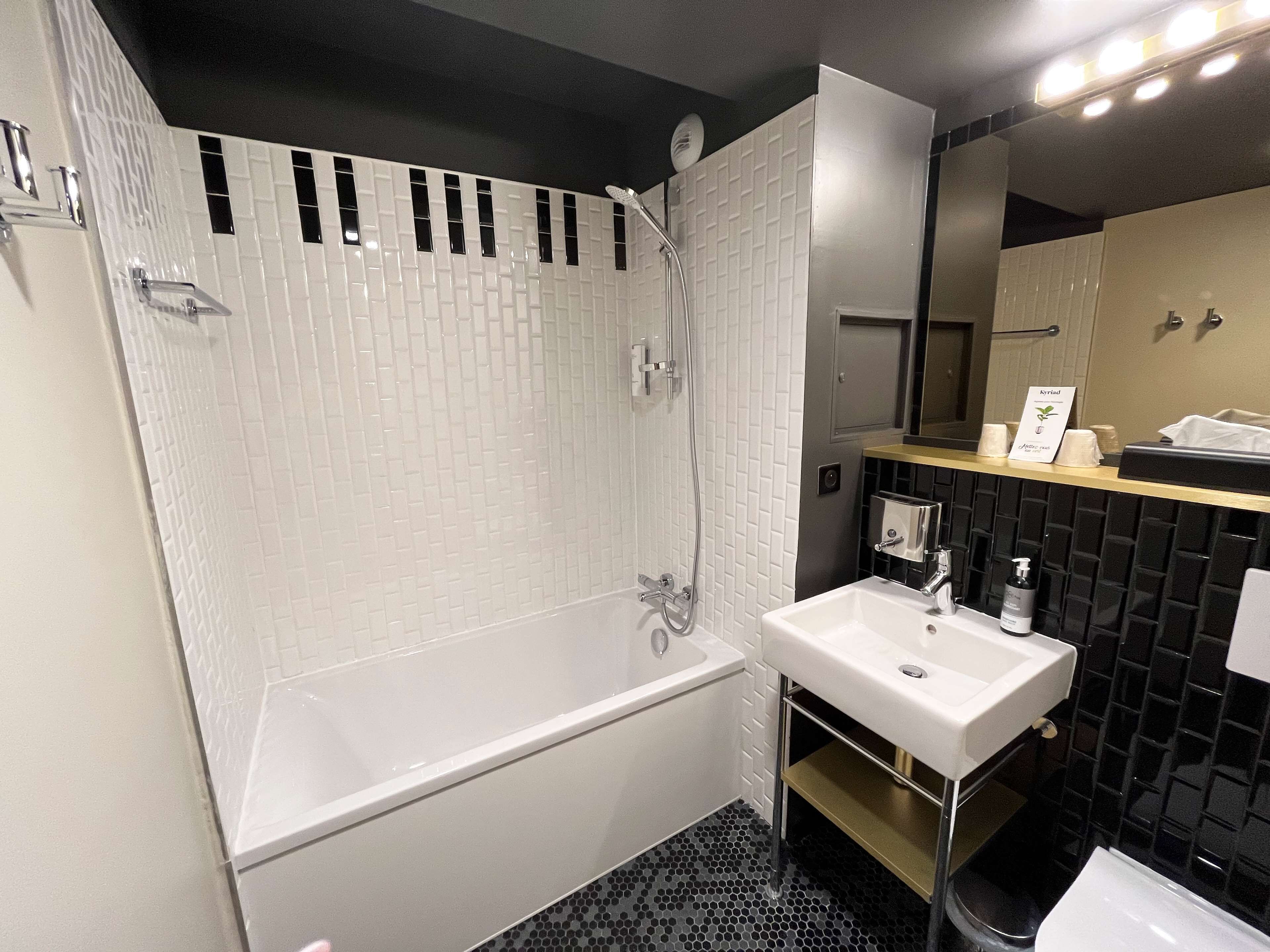 A modern bathroom with a white bathtub, a sink, and a mirror.