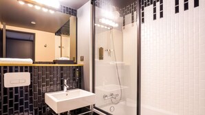 A modern bathroom with a glass-enclosed shower, a white sink, and a mirror above it. - Hotel Kyriad Créteil/Bonneuil-sur-Marne (Bonneuil-sur-Marne)