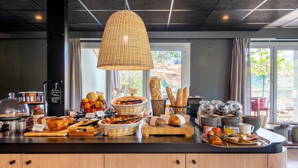 A breakfast buffet with various food items and a wicker hanging light fixture. - Campanile NATURE - Paris Ouest Gennevilliers Port (Gennevilliers)