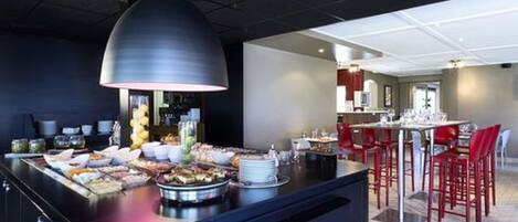 A modern kitchen with a central island, red chairs, and a dining area in the background.